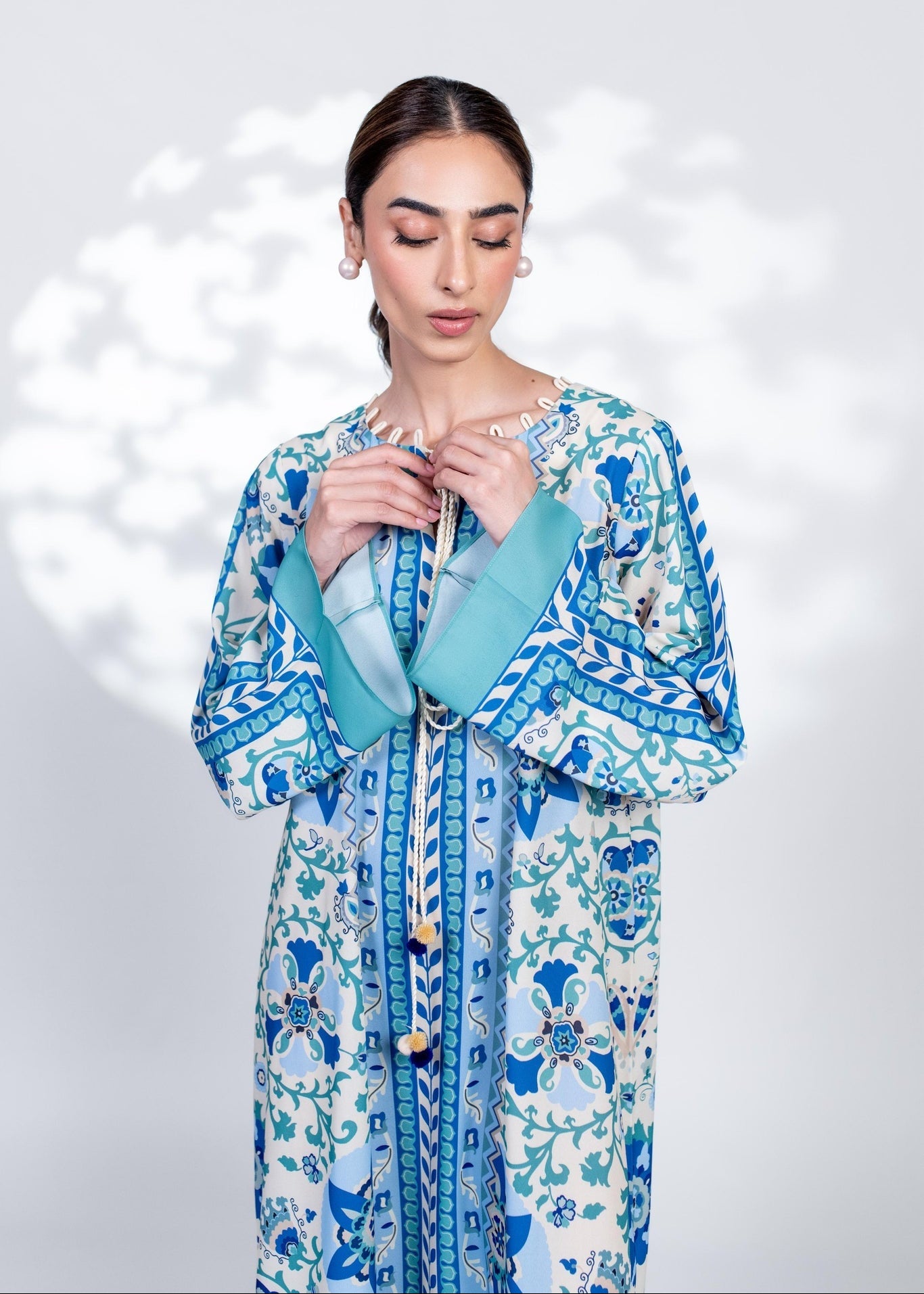 Woman wearing a blue and white floral dress with a matching shawl against a light gray background